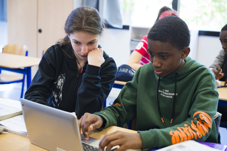 Deux élèves travaillant sur un ordinateur portable en classe